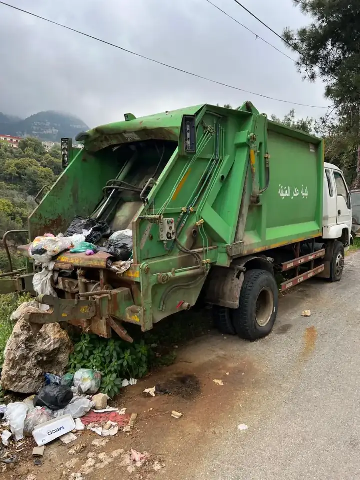Municipal waste collection truck with spilled waste beside it